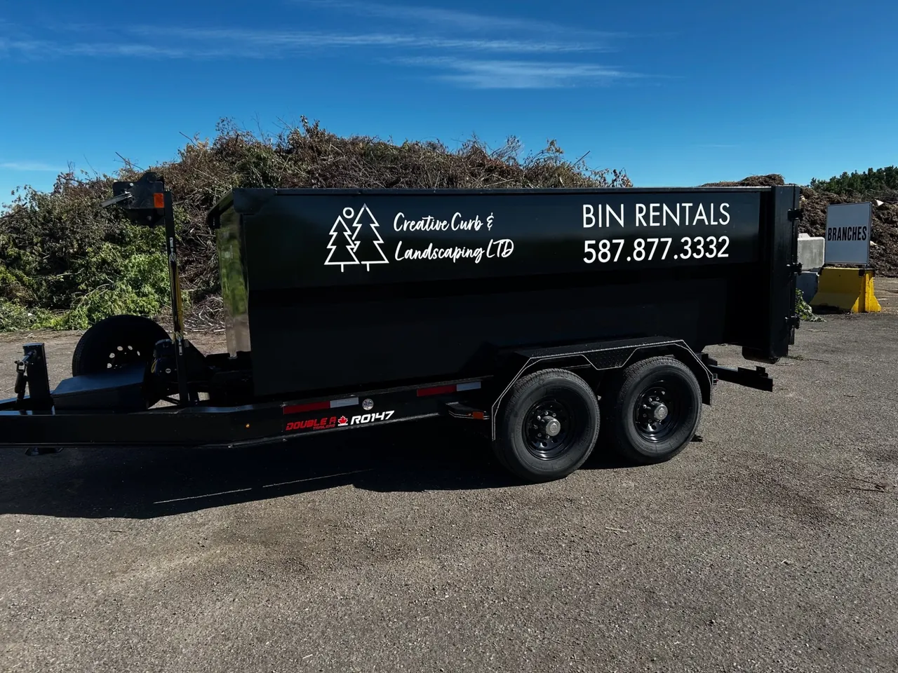 Side view of a 12-yard roll-off bin on a roll-off trailer